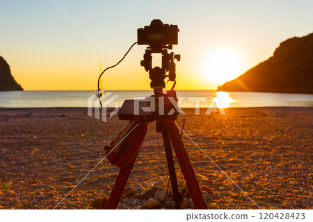 Camera taking picture of sunrise over sea surface Camera taking picture of sunrise over sea surface 120428423