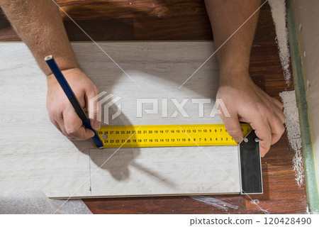 Man measuring floor panels 120428490