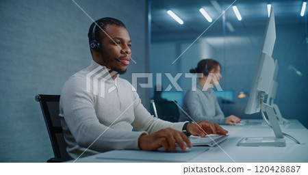African American hotline operator talks on headset with customer, works on computer African American hotline operator talks on headset with customer, works on computer 120428887