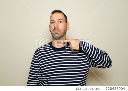 A bearded Hispanic man threatens to cut his throat. The man has a violent look and makes threatening gestures. The man threatens and looks for a fight. 120428904