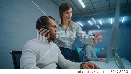 African American technical support specialist monitors data on computer with colleague 120428920