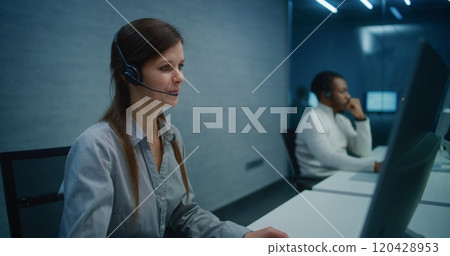 Female hotline operator wears headset, starts night shift providing online customer service Female hotline operator wears headset, starts night shift providing online customer service 120428953