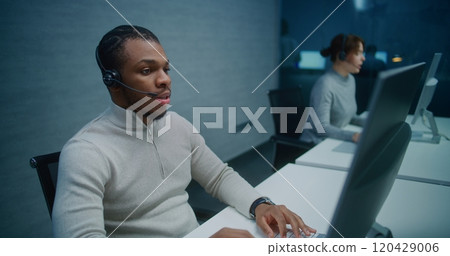 African American helpdesk specialist talks on headset with customer, works on computer African American helpdesk specialist talks on headset with customer, works on computer 120429006