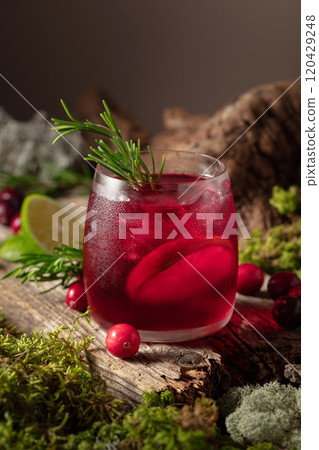Cranberry cocktail with ice, lime, and rosemary on a old wooden board. Cranberry cocktail with ice, lime, and rosemary on a old wooden board. 120429248