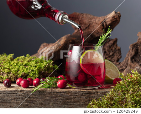 Cranberry cocktail with ice, lime, and rosemary on a old wooden board. Cranberry cocktail with ice, lime, and rosemary on a old wooden board. 120429249