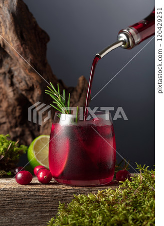 Cranberry cocktail with ice, lime, and rosemary on a old wooden board. Cranberry cocktail with ice, lime, and rosemary on a old wooden board. 120429251