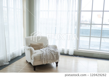 Stylish loft interior. Spacious design apartment with light walls large windows white armchair. Clean modern decoration with elegant furniture in minimalist Scandinavian style 120429262