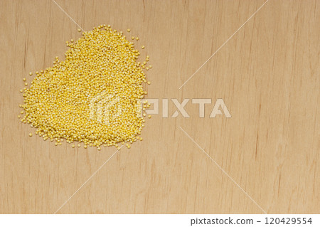 Millet groats heart shaped on wooden surface. Millet groats heart shaped on wooden surface. 120429554