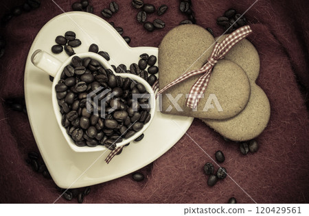 Coffee beans in heart shaped cup and dessert on brown 120429561
