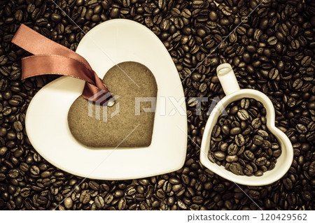 Heart shaped cup and cookie on coffee beans background 120429562