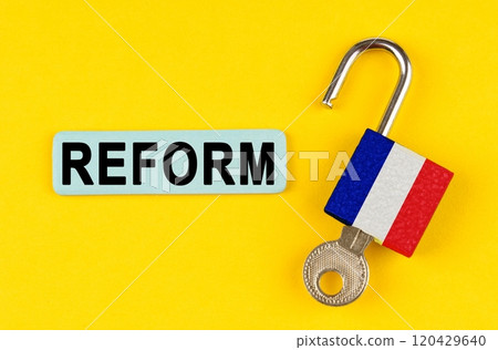 On the yellow surface is an open lock with a key and a sticker with the inscription - REFORM On the yellow surface is an open lock with a key and a sticker with the inscription - REFORM 120429640