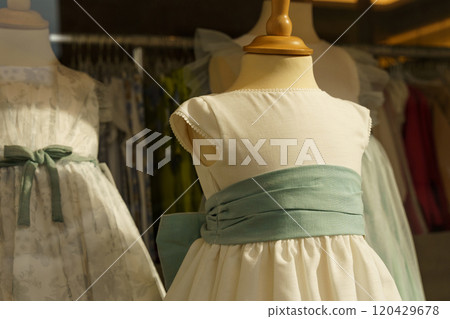 Showcase behind glass with formal children's dresses in a children's clothing store 120429678