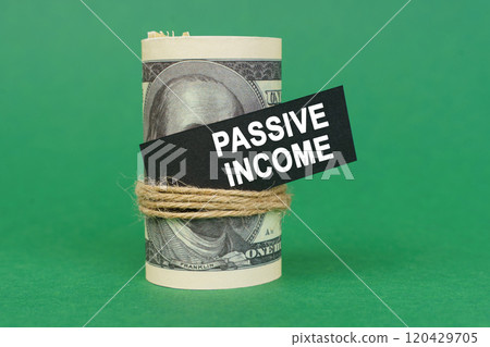 On a green surface, rolled dollars with a black sign that says - PASSIVE INCOME 120429705