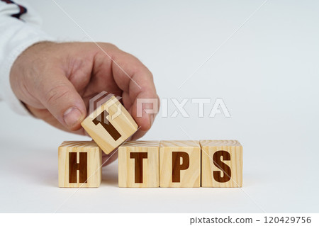 On a white surface, a man stacks cubes with the inscription - HTTPS 120429756