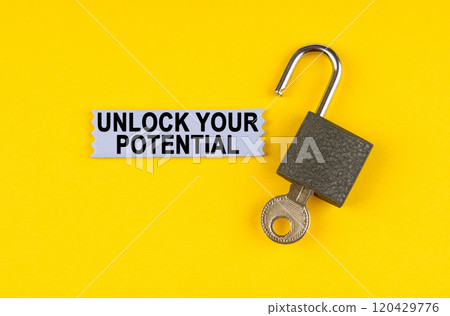 On the yellow surface lies an open lock with a key, next to it is a sticker with the inscription - UNLOCK YOUR POTENTIAL 120429776