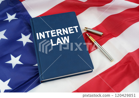 On the US flag lies a pen and a book with the inscription - INTERNET LAW On the US flag lies a pen and a book with the inscription - INTERNET LAW 120429851