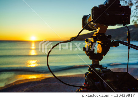 Camera taking picture film of sunrise over sea surface 120429917