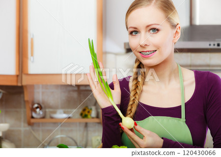Woman in kitchen holds green fresh chive 120430066