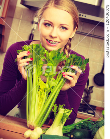 Woman in kitchen with green vegetables 120430079