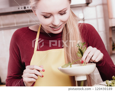 Woman in kitchen making vegetable smoothie juice 120430189