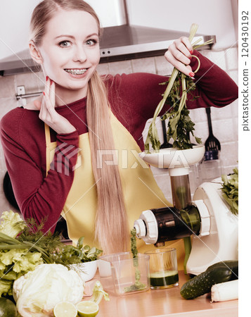 Woman in kitchen making vegetable smoothie juice 120430192