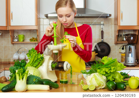 Woman in kitchen making vegetable smoothie juice 120430193