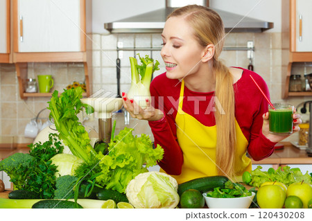 Woman in kitchen holding vegetable fennel smoothie juice 120430208