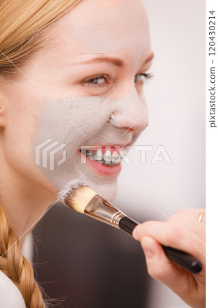 Woman applying with brush clay mud mask to her face 120430214