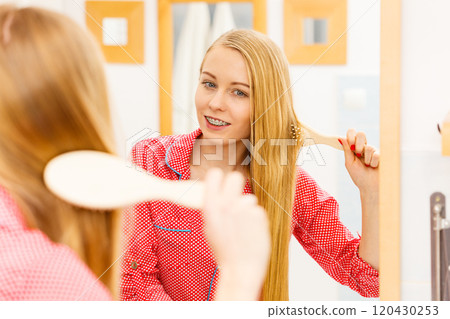 Woman brushing her long hair in bathroom 120430253