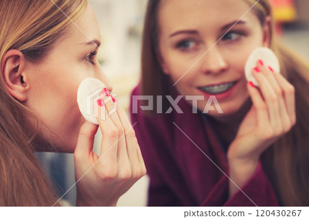 Woman using cotton pad to remove make up Woman using cotton pad to remove make up 120430267
