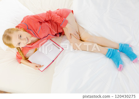 Woman relaxing in bed reading book 120430275