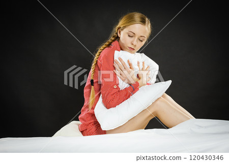 Sad depressed girl in bed gripping pillow 120430346