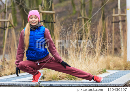 Woman wearing sportswear exercising outside during autumn 120430397