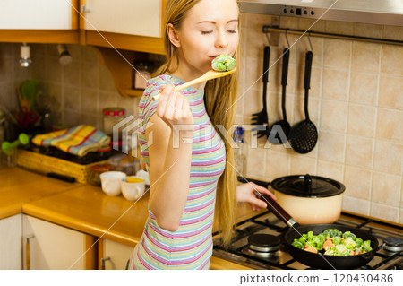 Woman cooking stir fry frozen vegetable on pan 120430486
