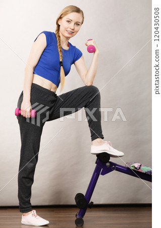 Teenage woman working out at home with dumbbell 120430508