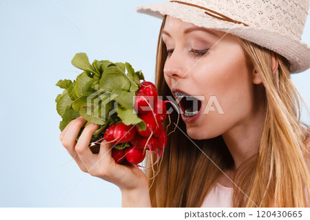 Happy woman biting radish 120430665