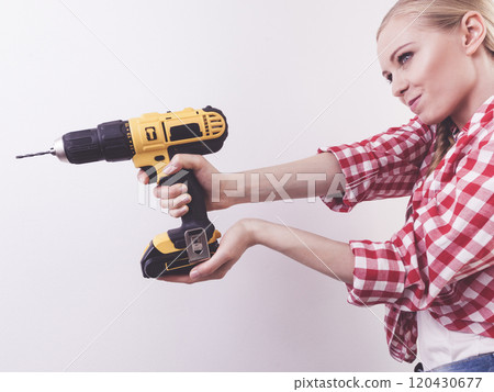 Woman using drill on wall 120430677