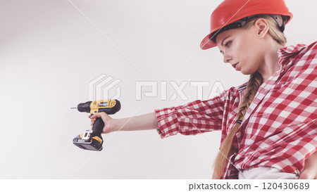 Woman using drill on ladder 120430689