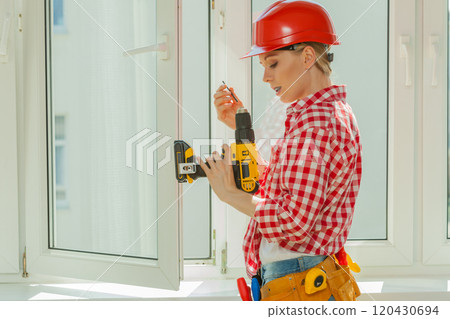 Woman using drill on window Woman using drill on window 120430694