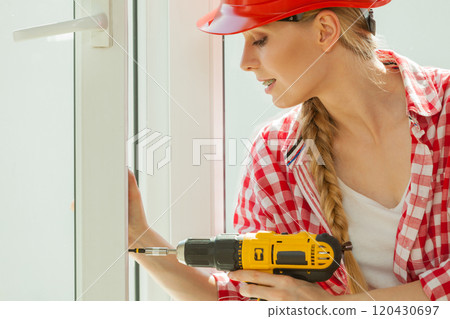 Woman using drill on window 120430697
