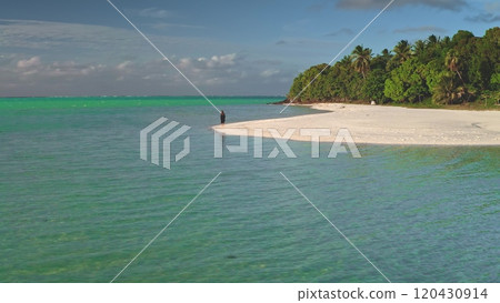 Lone woman is walking on a pristine white sand beach on the tropical island of maupiti, french polynesia, surrounded by turquoise waters 120430914
