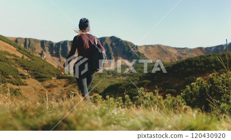 Tourist woman hike trekking trail in autumn mountains. Girl with backpack walking highland meadow in sunset light. Travel, tourism, hiking, freedom and active lifestyle concept. Slow motion, back view Tourist woman hike trekking trail in autumn mountains. Girl with backpack walking highland meadow in sunset light. Travel, tourism, hiking, freedom and active lifestyle concept. Slow motion, back view 120430920