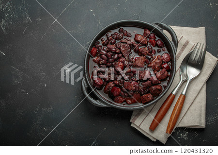 Brazilian feijoada with black beans, sausage and meat in a pot, top view with space for text 120431320