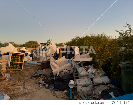 Urban Waste Piles Create an Unsightly View in a Neglected Area Near Trees at Sunset 120431335