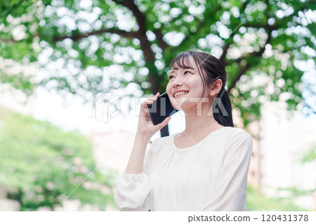 Young woman making a phone call outside 120431378