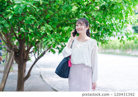 Young woman making a phone call outside 120431392