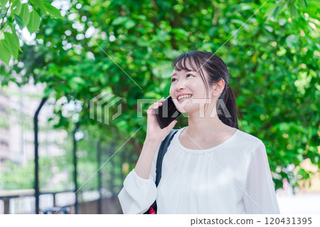 Young woman making a phone call outside 120431395