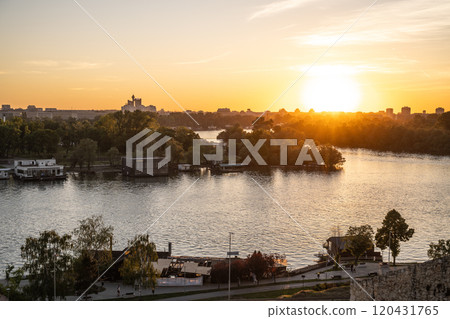 View of the Sava River at sunset from Kalemegdan fortress in Belgrade, Serbia. The golden hues reflect on the water, highlighting the surrounding landscape and charming riverbanks. View of the Sava River at sunset from Kalemegdan fortress in Belgrade, Serbia. The golden hues reflect on the water, highlighting the surrounding landscape and charming riverbanks. 120431765