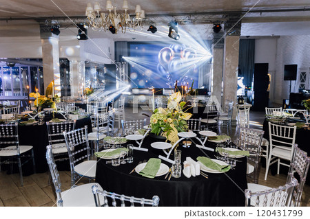 Elegant banquet hall with floral centerpieces, table settings, dramatic stage lighting for events 120431799