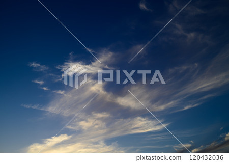 Beautiful wispy clouds dance across the evening sky at twilight, creating a stunning backdrop for reflection 120432036